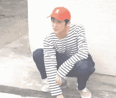 a man wearing a striped shirt and a red hat with a skull and crossbones on it