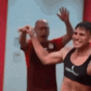 a man and a woman are standing next to each other in a room and waving .
