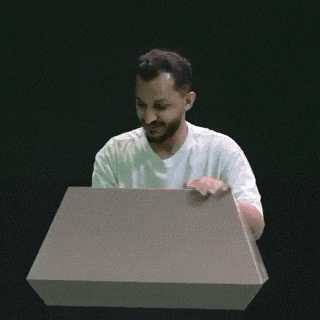 a man in a white shirt is sitting at a podium with a box in front of him