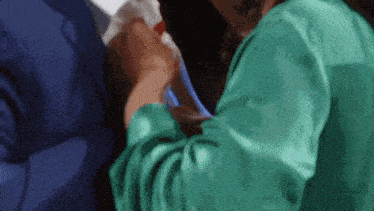 a woman in a green top is holding a man 's arm
