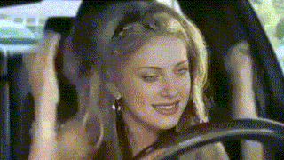 a woman is sitting in the driver 's seat of a car with her hands in the air .
