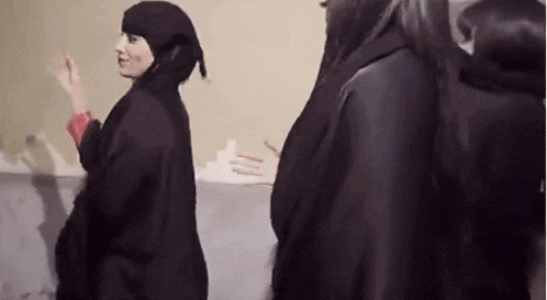 a woman in a black hijab is standing next to another woman in a black dress .