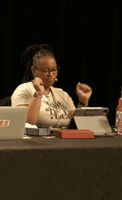 a woman sitting at a table with a sticker on her shirt that says tic