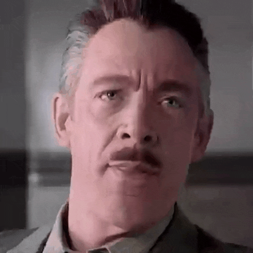a close up of a man 's face with a mustache making a funny face .
