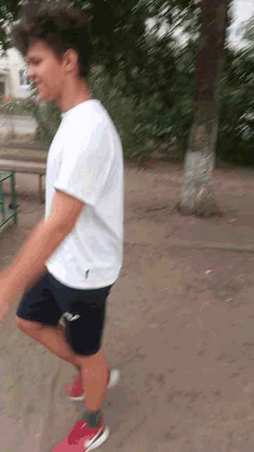 a blurry picture of a boy wearing a white shirt and fila shorts