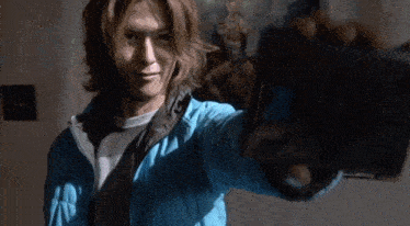 a man in a blue jacket is holding something in his hand .