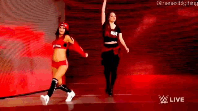 two female wrestlers are dancing on a stage in front of a crowd .