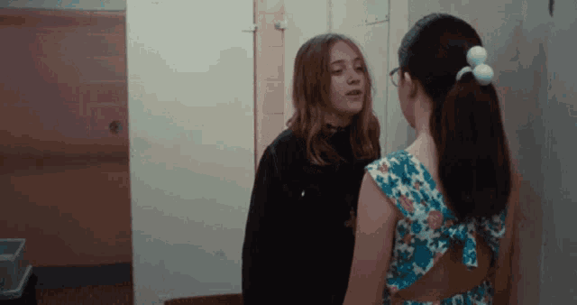 two girls are standing next to each other in a hallway