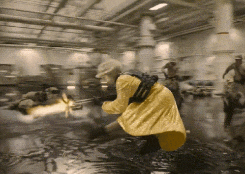 a woman in a yellow coat is kneeling in the water