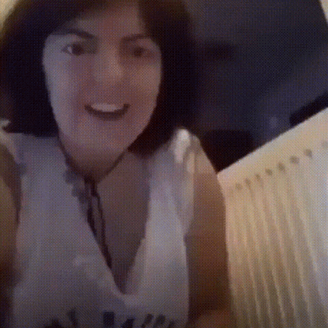 a woman is smiling and looking at the camera while wearing a white shirt .