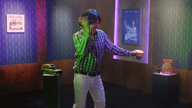 a man in a plaid shirt is dancing in front of a sign that says let 's go boom