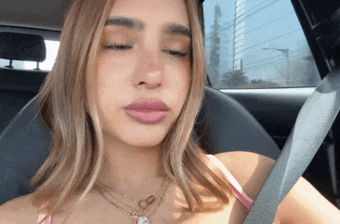 a woman wearing a necklace is sitting in a car