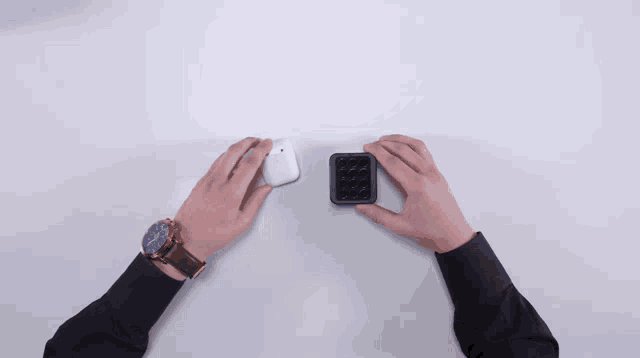 a person 's hands are reaching for an airpods case on a table