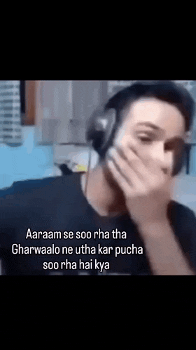 a man wearing headphones is covering his mouth .