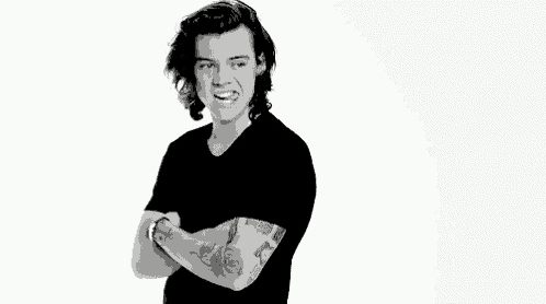 harry styles is wearing a black shirt with his arms crossed and making a funny face .