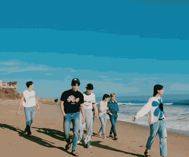 a group of people walking on a beach with one wearing a sweater that says flowers