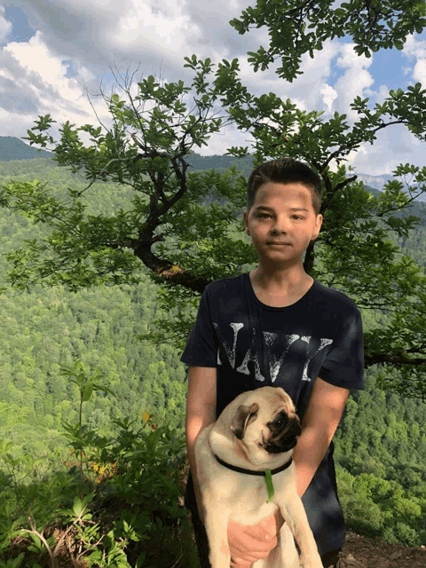 a boy wearing a navy shirt holds a dog
