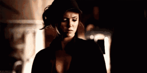 a woman wearing a hat and a black shirt is standing in the dark .