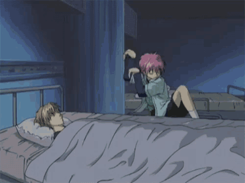 a girl with pink hair sits on a bed next to another girl