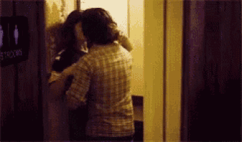 a couple kissing in a room with a sign that says tb
