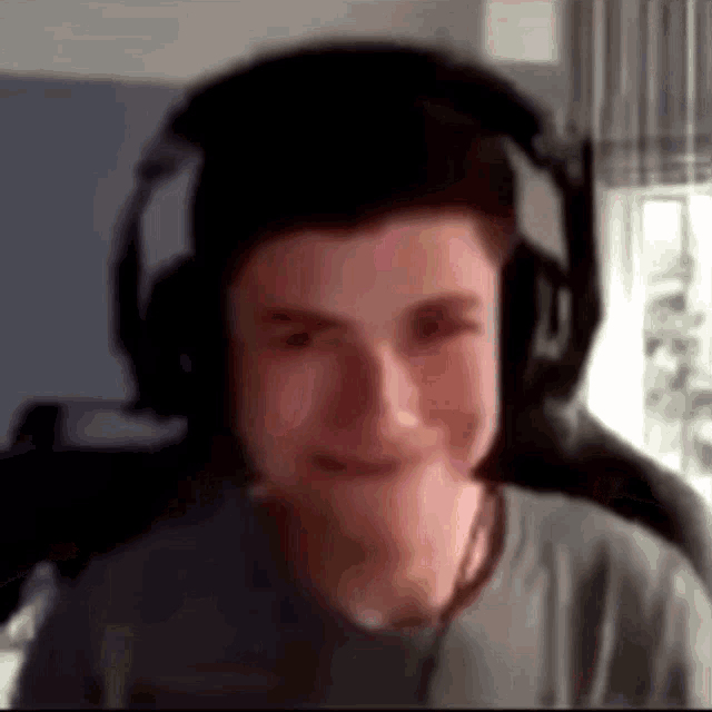 a young man wearing headphones is making a funny face while sitting in a chair .