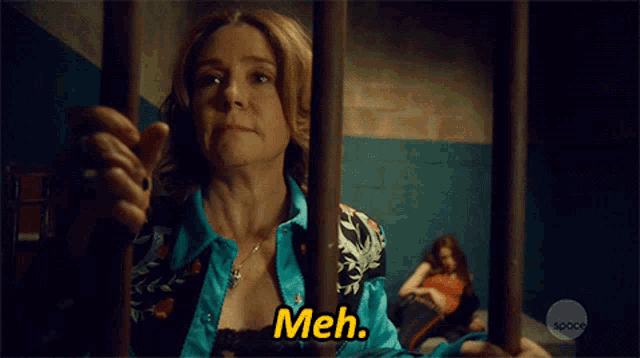a woman in a blue shirt is behind bars and the caption says meh