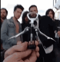 a man is holding a corkscrew in front of a group of people .
