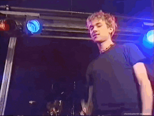 a man in a black shirt stands in front of a blue light .