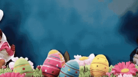 easter eggs and flowers on a blue background with a rabbit in the background