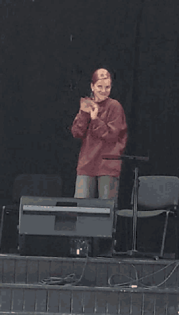 a girl in a red sweater is standing on a stage