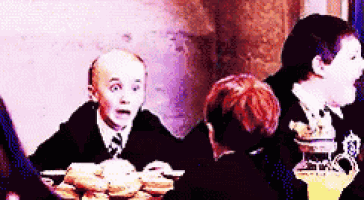 a group of children are sitting at a table eating food and drinking juice .