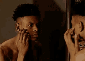 a man is looking at his face in a mirror .
