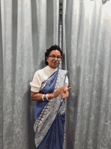 a woman wearing glasses and a blue and white striped blanket giving a thumbs up