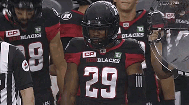 a football player with the number 29 on his jersey stands with his teammates
