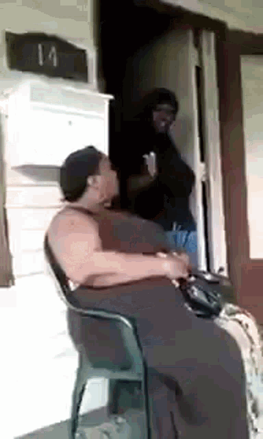 a woman is sitting in a chair in front of a door while a man stands behind her .
