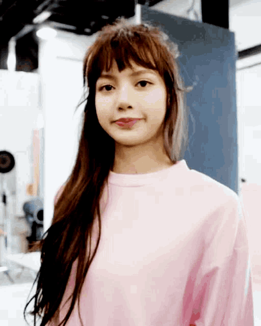 a girl with long hair and bangs is wearing a pink sweater