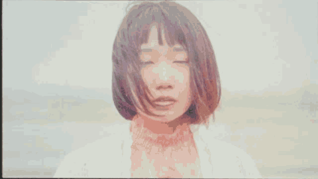 a woman with her eyes closed is wearing a white sweater