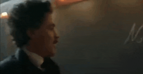 a man in a suit and tie is standing in a dark room in a room .