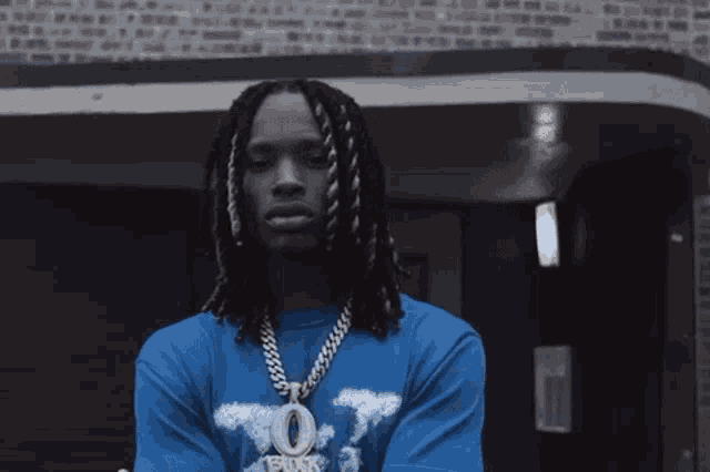 a man with dreadlocks wearing a blue shirt that says o block