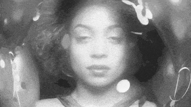 a black and white photo of a woman 's face with the letter d in the background