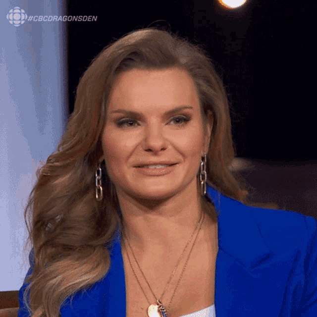 a woman wearing a blue jacket and a necklace with the hashtag #cbcdragonsden at the bottom