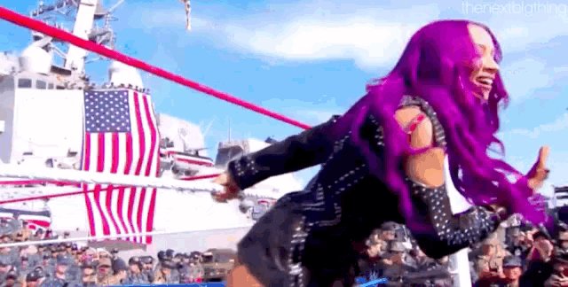 a woman with purple hair is standing in a wrestling ring with a flag in the background .