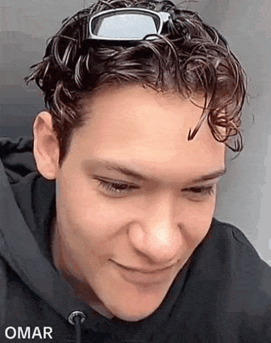 a close up of a young man wearing sunglasses and a black hoodie .