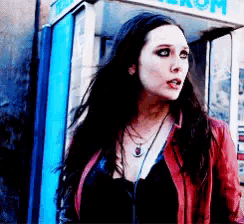 a woman in a red jacket is standing in front of a phone booth that says telekom