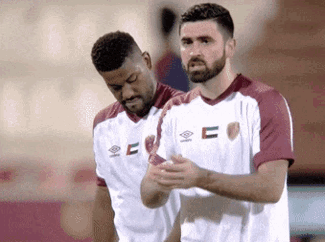 two soccer players wearing jerseys that say e on them