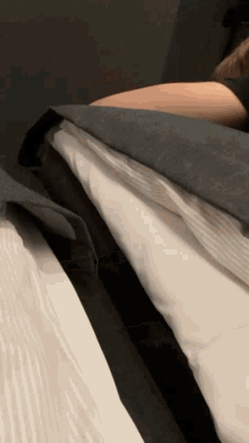 a person is laying on a bed with pillows and a blanket