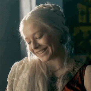 a woman with blonde hair is smiling with her eyes closed and a braid in her hair .