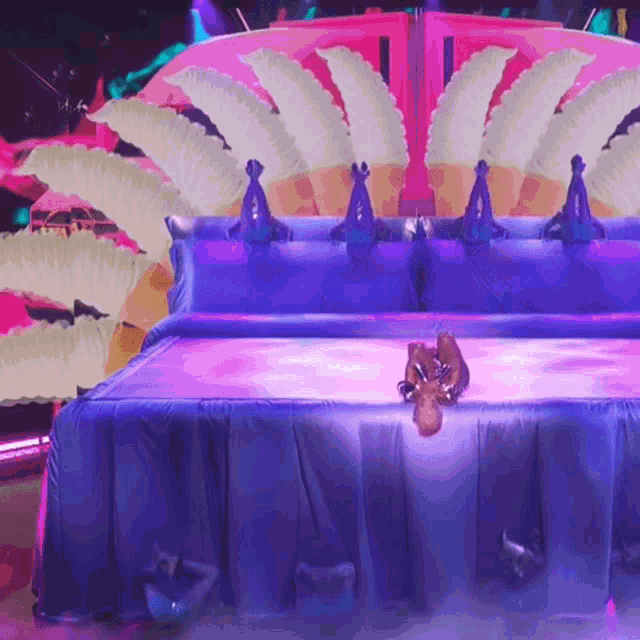 a person is laying on a bed with purple sheets and feathers on it
