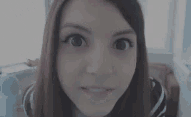 a close up of a woman 's face making a funny face while looking at the camera .
