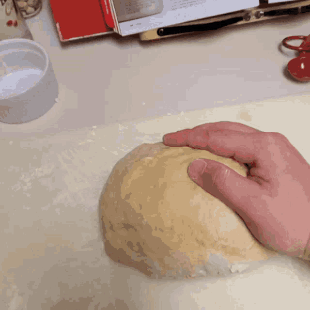 a person is kneading a ball of dough on a counter